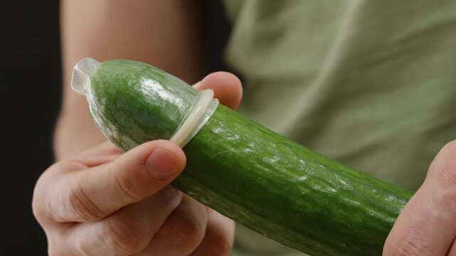A Man Removing a Condom from a Cucumber During a Sex Education Lesson