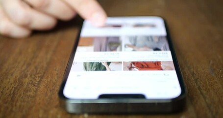 Woman browsing fashion clothing in an online store, shopping directly via smartphone. Mobile online shopping concept. - Powered by Adobe