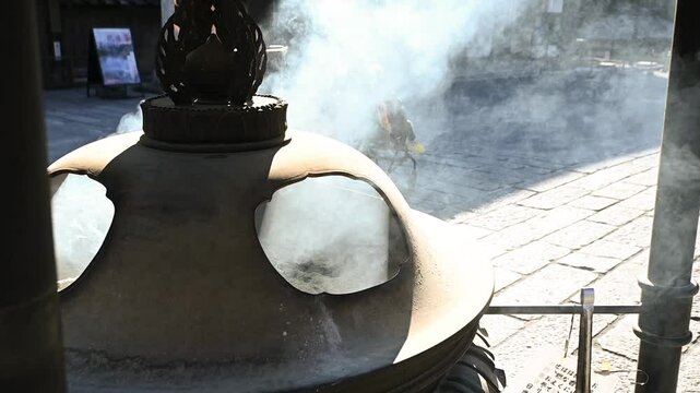 Jokoro, slow motion of smoke from a large earthenware outdoor at a Japanese temple at daytime in Nikko on the countryside of Japan.
