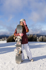 Smiling snowboarder standing on a snow-covered slope under blue skies