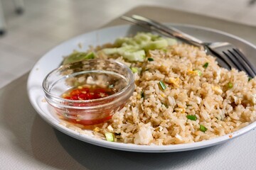 A plate of crab fried rice with fresh cucumber slices, lime, and chilli fish sauce at a street food stall in Silom - Bang Rak, Bangkok, Thailand