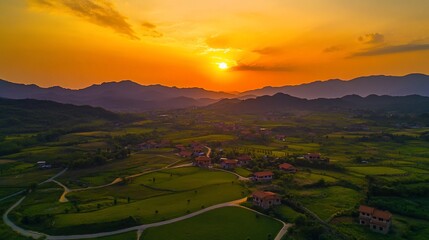 Fototapeta premium Golden Sunset over Rural Landscape with Mountains and Houses in Scenic Valley View