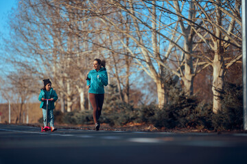 Obraz premium Happy Family Practicing Sports in the Park Together. Cheerful Mother and Daughter running together outside in nature 