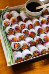 Freshly prepared spring rolls served with dipping sauce on a wooden table