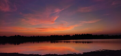 Stunning sunset over tranquil lake, reflecting warm hues of orange,pink,blue. Peaceful water and soft sky create serene and dreamy atmosphere, perfect for backgrounds, nature prints, landscape themes.