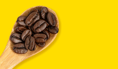 Close-up of roasted coffee beans on a wooden spoon, placed on a wooden background, perfect for coffee-related designs and concepts.