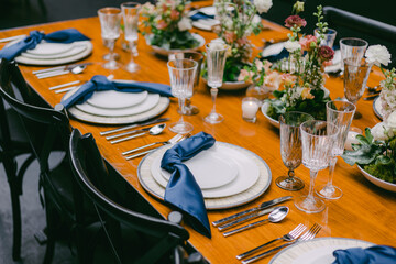 Elegant table setting with blue napkins and floral centerpieces for a special event in a stylish venue