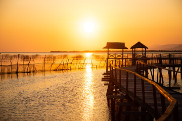 Fototapeta premium sunset on an exotic wooden bridge with the silhouette of a gate on a beautiful beach