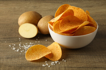 Potato chips in a bowl on a wooden background