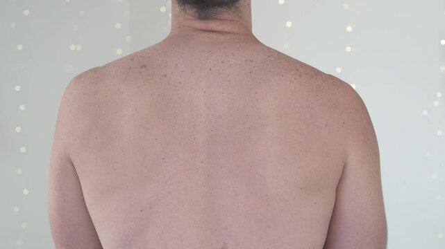 A shirtless man stretching his shoulders and elbows, emphasizing back muscles and neck alignment. Concept of physical fitness, body posture, and health awareness.