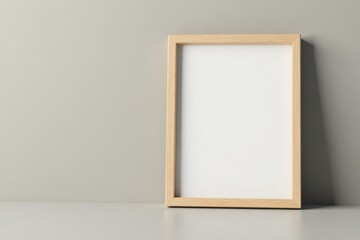 A simple, light wooden frame rests on a surface against a neutral backdrop, ready for a cherished memory or artwork