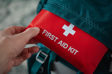 A person is carefully holding a bright red first aid kit in their hand, ready to respond to any emergency situation that may require medical assistance and supplies at a moments notice