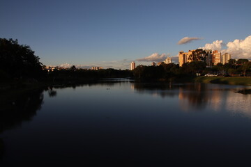 View of a late afternoon at the Indaiatuba Ecological Park, a city in the countryside of the state of S&atilde;o Paulo - Brazil. Gradient sky, shade of trees and reflection of buildings in the lake water