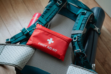 A vibrant red first aid kit is prominently perched atop a sturdy backpack, ready for any...