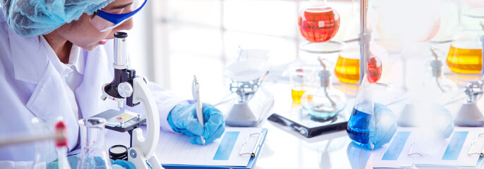 Fototapeta premium Banner Scientist woman holding chemical test yellow glass tube testing science laboratory. Lab technician holding gold fluid dropper glass tube Urine sample. Asian woman scientist with copy space