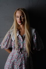 A young woman in a floral dress poses elegantly against a dark background