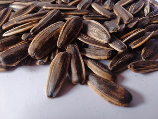 Kuaci or kwatji sunflower seeds. Scattered on a wooden table. Snack on dried and salted sunflower seeds. Selective focus