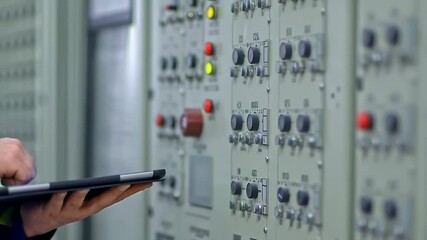 Engineer using tablet to control industrial panel - Powered by Adobe