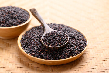 Organic rice berry or purple rice on wooden plate with spoon, Thai rice