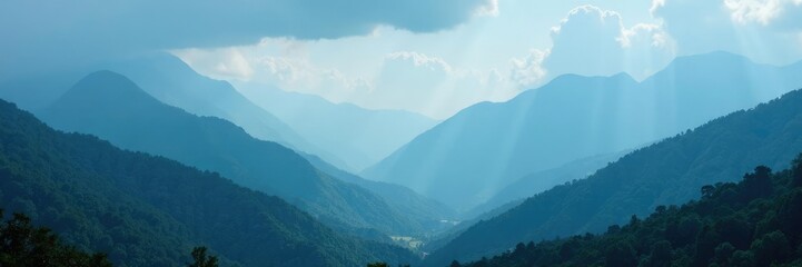 Obraz premium misty mountains rise up from the valley below under an overcast blue sky, landscape, mist