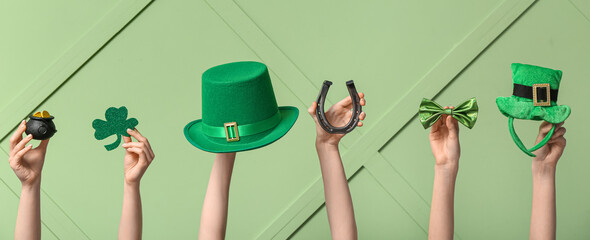 Female hands holding different party decor for St. Patrick's Day celebration on green background