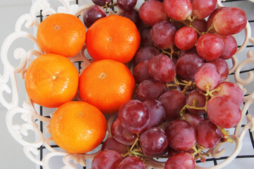 Red grapes and oranges collected in one fruit basket
