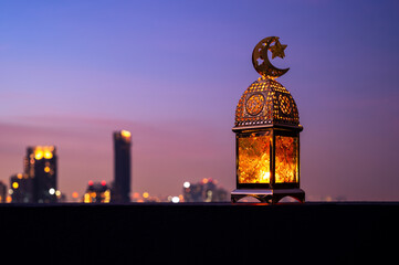Golden lantern that have moon symbol on top with dusk sky and city background