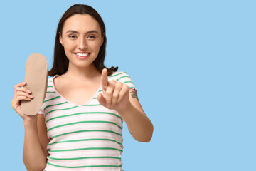Beautiful young woman with reusable menstrual pad on blue background