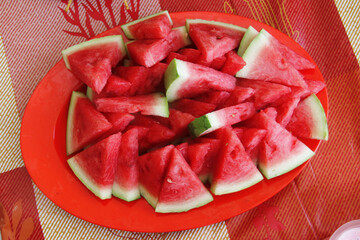 Fresh watermelon with red flesh, cut into pieces and served on a plate