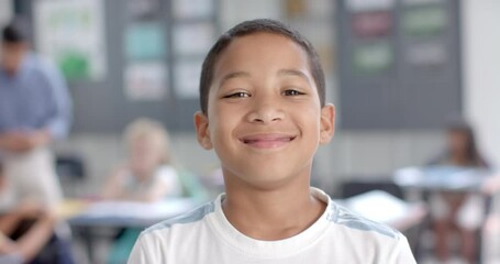 Biracial boy smiles brightly in a classroom setting at school
