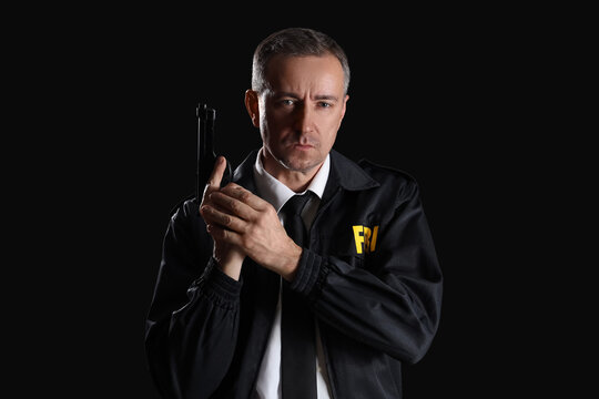 Mature FBI agent with gun on black background