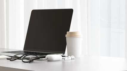 Desktop of modern gray desk with computer laptop, notebook, eyeglasses, coffee cup, smartphone, earphone in sunlight from window for home office working, technology, lifestyle product background 3D