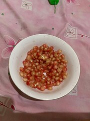 Delicious Red juicy Pomegranate grains seeds on a white plate 
