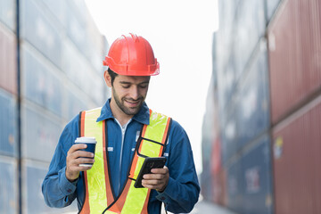 Male worker container yard take a break and using mobile phone at containers cargo site
