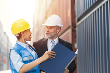 Senior businessman manager and asian woman worker working at container cargo site control loading containers boxes and checking up goods and shipping containers
