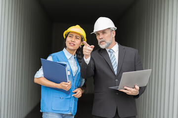 Senior businessman manager and asian woman worker working at container cargo site control loading containers boxes and checking up goods and shipping containers