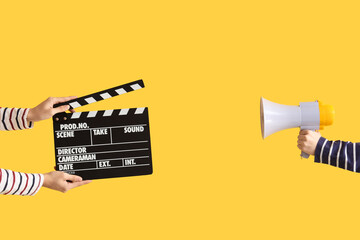 Hands with movie clapper and megaphone on yellow background