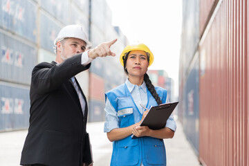 Senior businessman manager and asian woman worker working at container cargo site control loading containers boxes and checking up goods and shipping containers