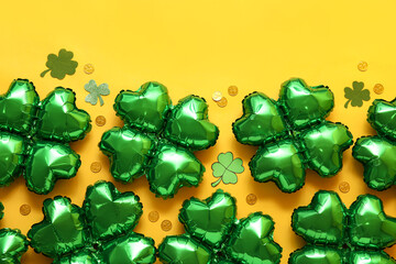 Balloons in shape of clover and coins on yellow background. St. Patrick's Day celebration