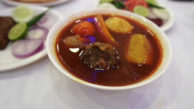 Closeup footage featuring Aminia special mutton curry prepared in Indian style dipped in oily gravy.