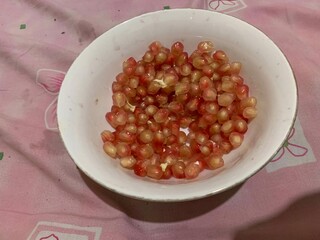 Delicious Red juicy Pomegranate grains seeds on a white plate 