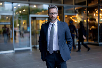 Fototapeta premium Successful mature businessman man in business suit standing outdoor on the way to working office