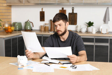 Young man in debt with papers at home