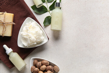 Bowl of shea butter with bottles of cosmetic oil, soap bar and nuts on white background