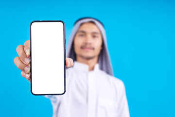 Selective Focus Of Blank Screen Smartphone For Mockup Againts Young Arabian Man Background 