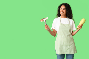 Beautiful young happy African-American woman with fresh and grilled zucchini on green background