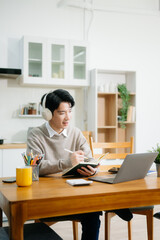 Young man using laptop while sitting at home. Young woman sitting in kitchen and working