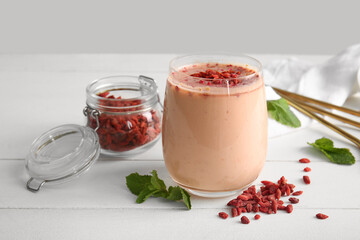 Glass of fresh goji berry smoothie with mint on white wooden table