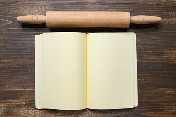 Blank recipe book and rolling pin on wooden background
