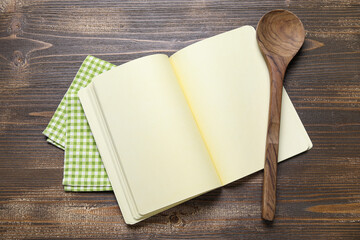 Blank recipe book, spoon and napkin on wooden background